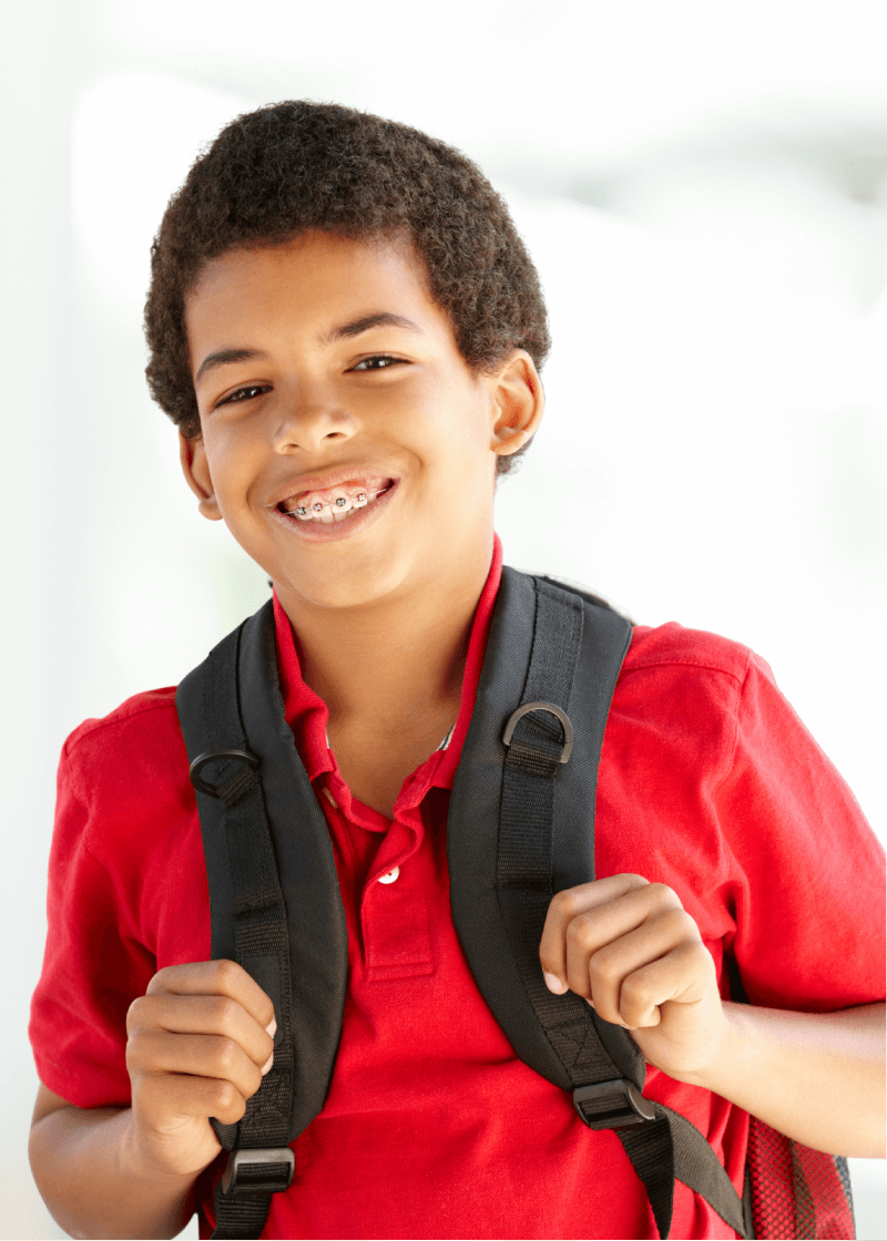 Smiling boy with braces wearing a red shirt and backpack