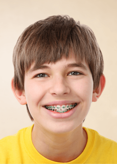 Smiling boy with metal braces wearing a yellow shirt