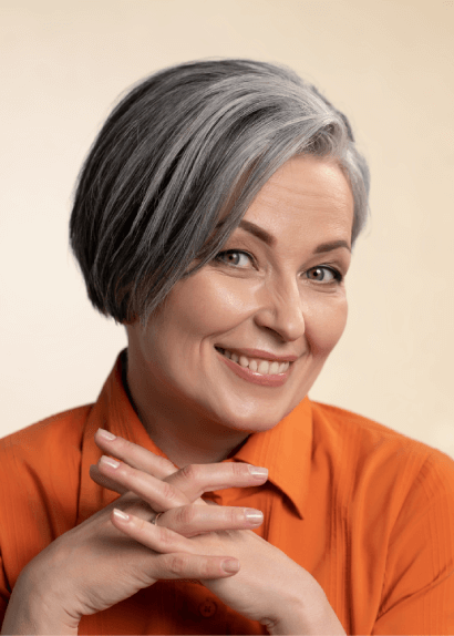 Smiling middle-aged woman with short gray hair in orange blouse