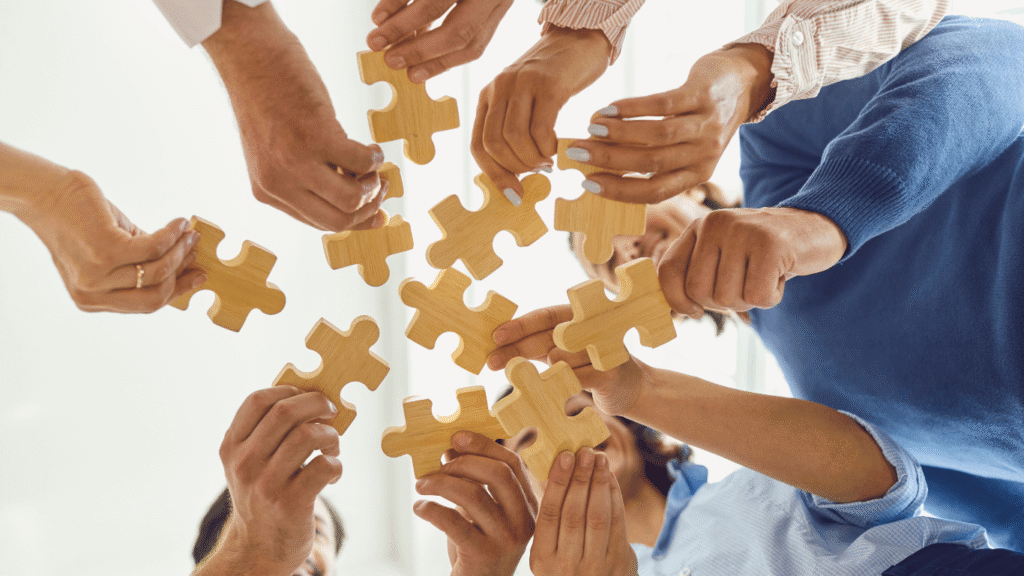 Hands of multiple people connecting jigsaw puzzle pieces