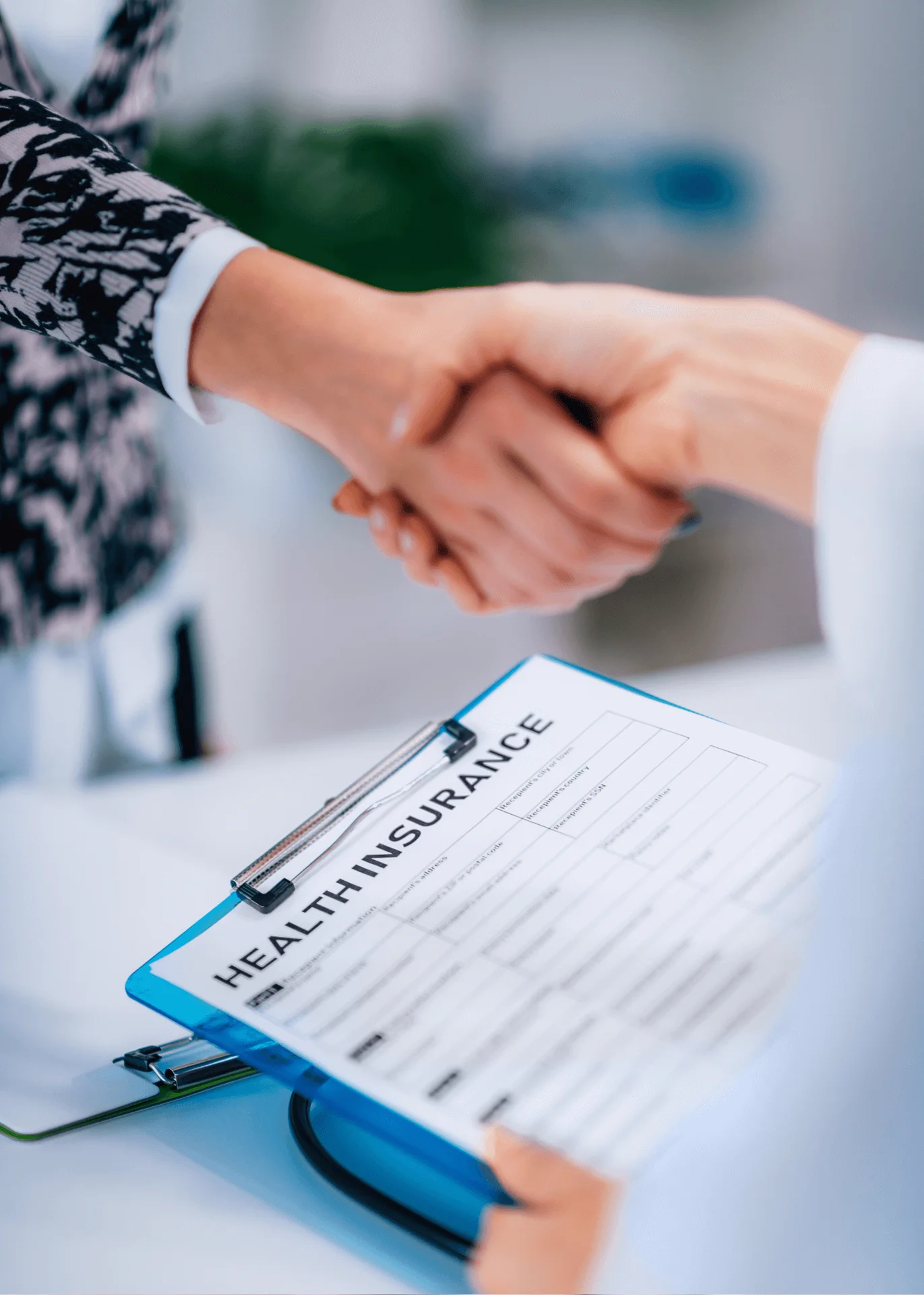 Two people shaking hands over a clipboard with a health insurance form