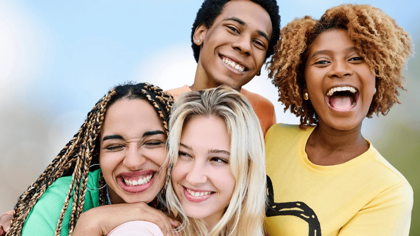 Group of diverse young friends laughing and hugging outdoors
