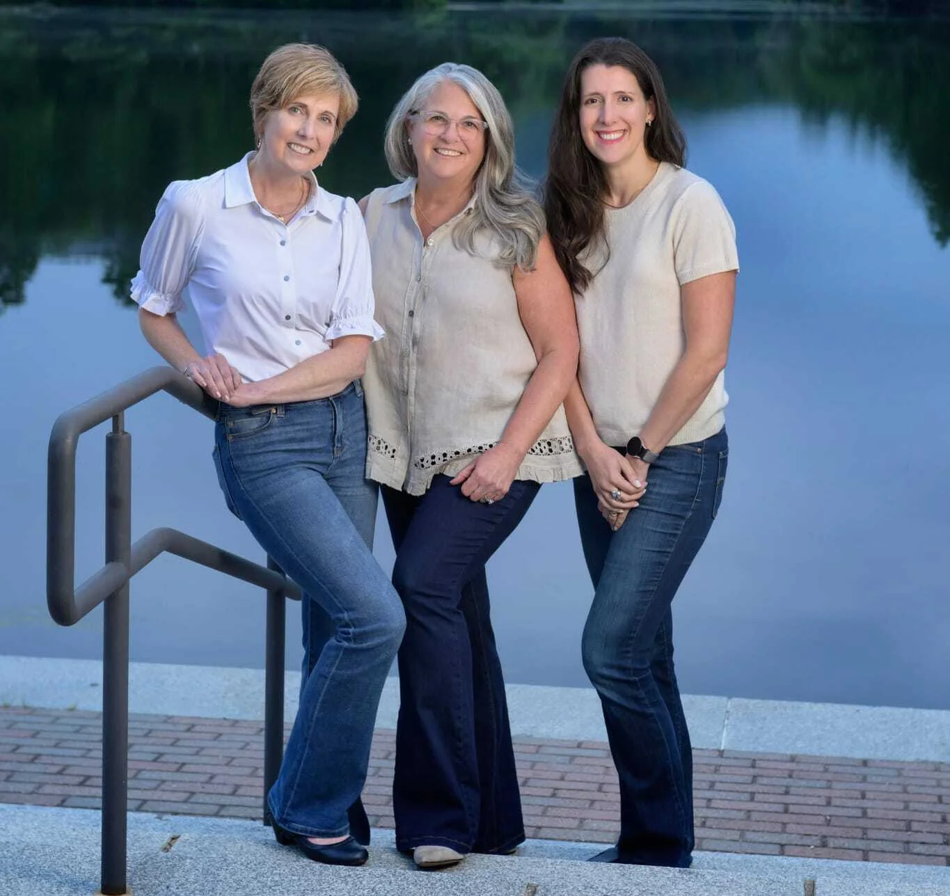 Three women orthodontists posing together by a lake at dusk