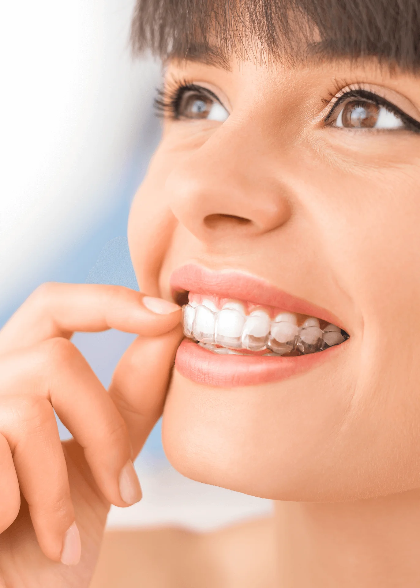 Close-up of a woman placing a clear Invisalign aligner over her teeth